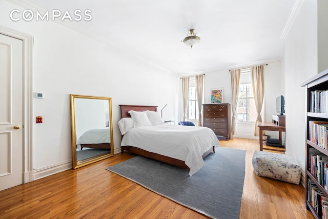 bedroom featuring crown molding and light wood finished floors
