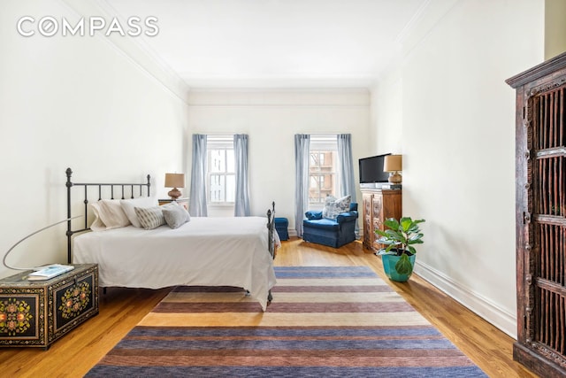 bedroom featuring crown molding, wood finished floors, and baseboards