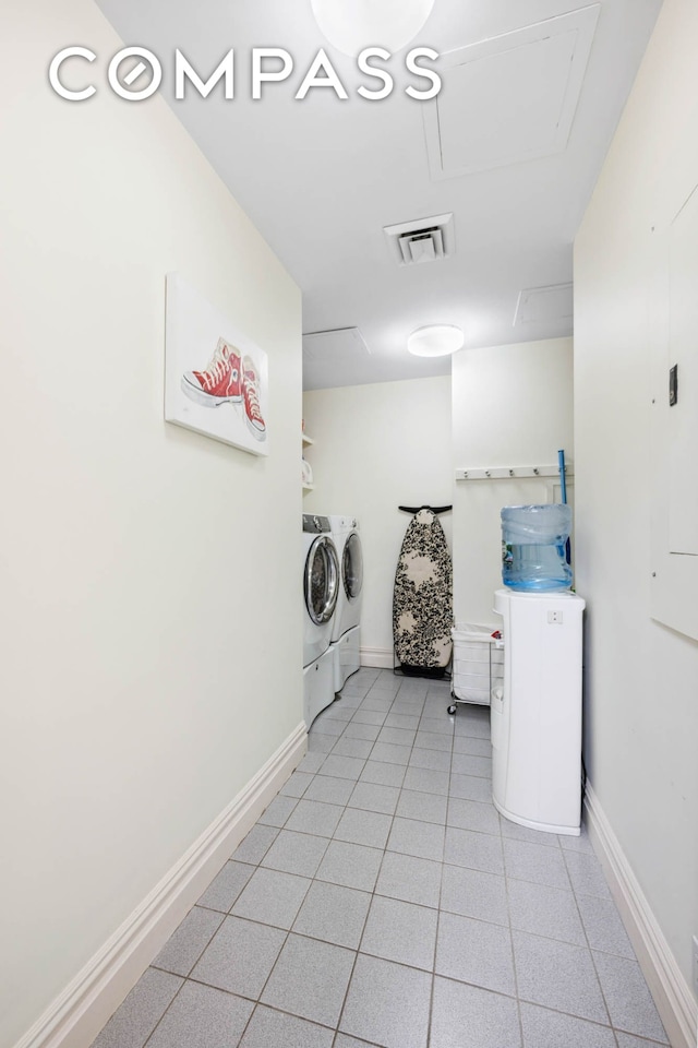 washroom featuring separate washer and dryer, light tile patterned flooring, and baseboards