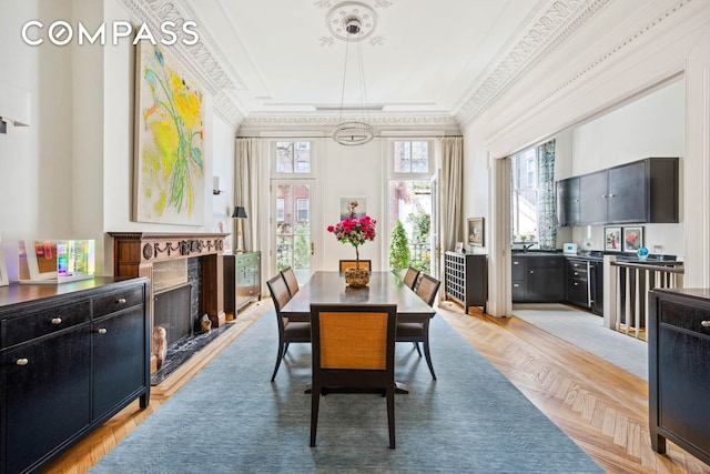 dining room with ornamental molding, a high end fireplace, and a tray ceiling
