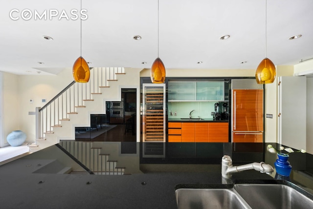 kitchen featuring beverage cooler, a sink, built in fridge, and dark countertops