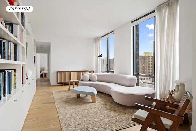 23 W 116th St Unit 12D, New York City, NY 10026 - living area featuring floor to ceiling windows, radiator, light wood-style flooring, and a city view