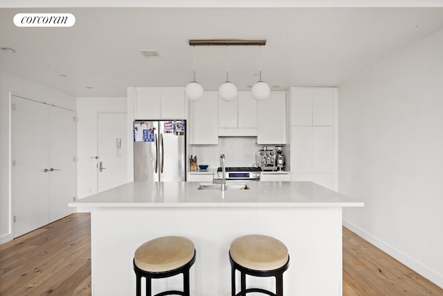 23 W 116th St Unit 12D, New York City, NY 10026 - kitchen with freestanding refrigerator, light wood finished floors, a sink, an island with sink, and a breakfast bar
