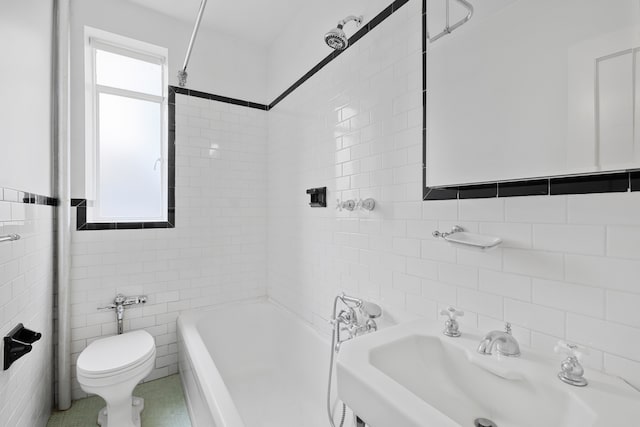 bathroom featuring toilet, a sink, shower / washtub combination, and tile walls