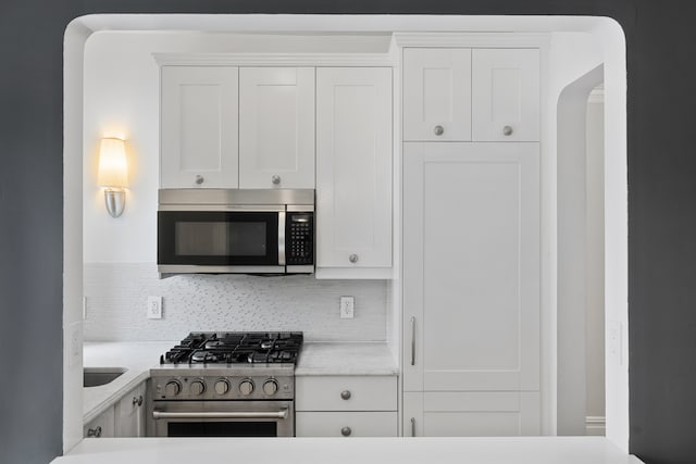 kitchen with white cabinets, backsplash, and stainless steel appliances