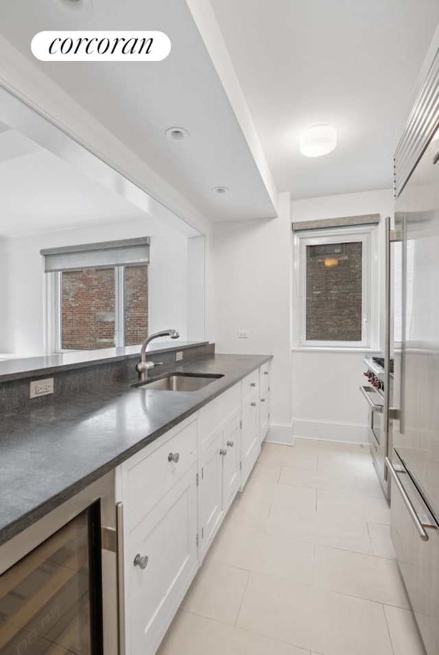 530 Park Ave Unit 5H, New York City, NY 10065 - kitchen featuring a sink, wine cooler, dark countertops, white cabinets, and baseboards