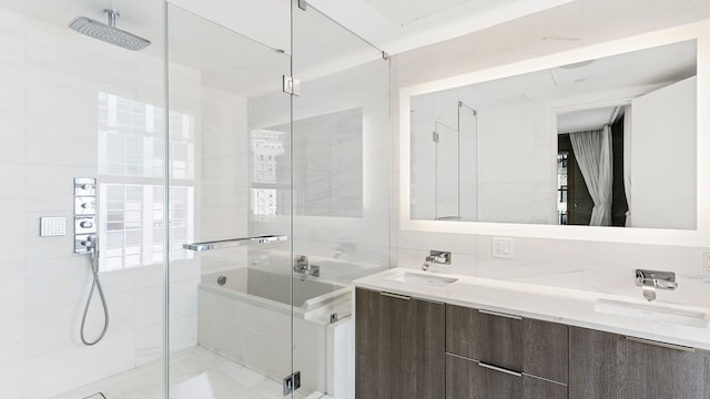 full bath with tile walls, a sink, double vanity, and a stall shower