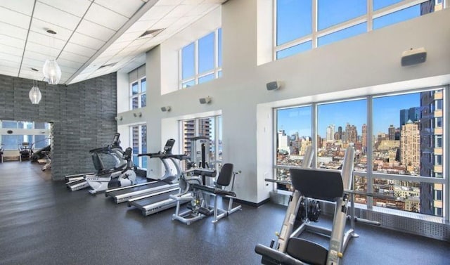 gym with a high ceiling, a view of skyline, and a paneled ceiling