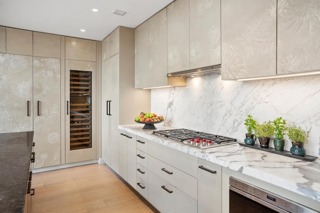 438 E 12th St Phd, Phd, New York City, NY 10009 - kitchen featuring light stone countertops, light wood finished floors, stainless steel gas cooktop, tasteful backsplash, and visible vents