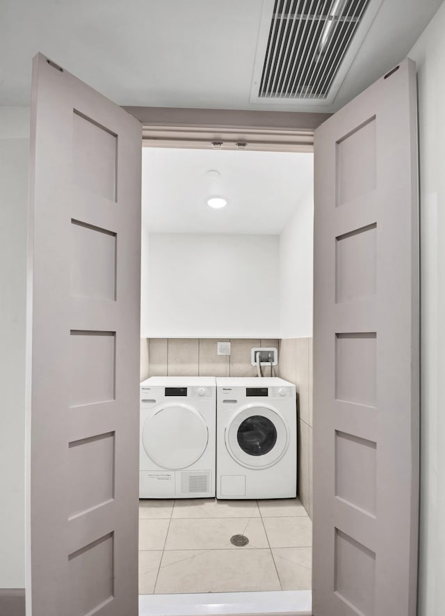 57 W 130th St Pha, Pha, New York City, NY 10037 - washroom featuring separate washer and dryer, light tile patterned floors, and tile walls