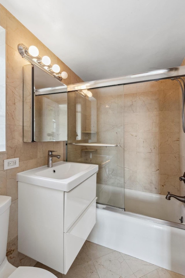 full bath featuring toilet, tile walls, enclosed tub / shower combo, vanity, and marble finish flooring