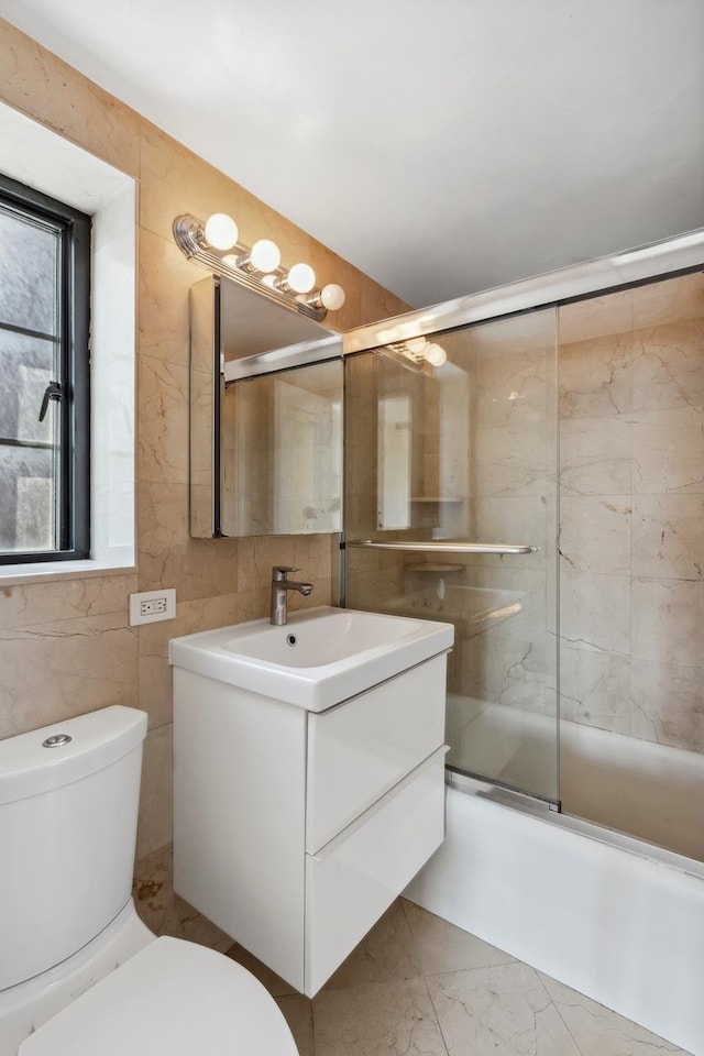 full bathroom with toilet, vanity, marble finish flooring, combined bath / shower with glass door, and tile walls