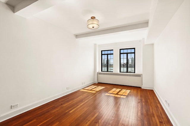 empty room featuring radiator, wood-type flooring, and baseboards