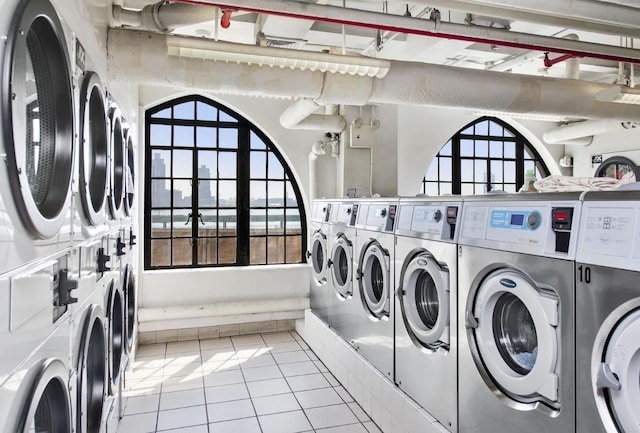 community laundry room with stacked washing machine and dryer, washer and dryer, and tile patterned flooring