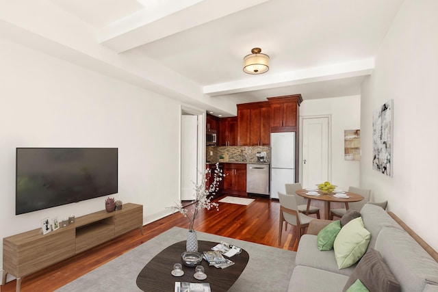 living area featuring dark wood-style floors, beamed ceiling, and baseboards