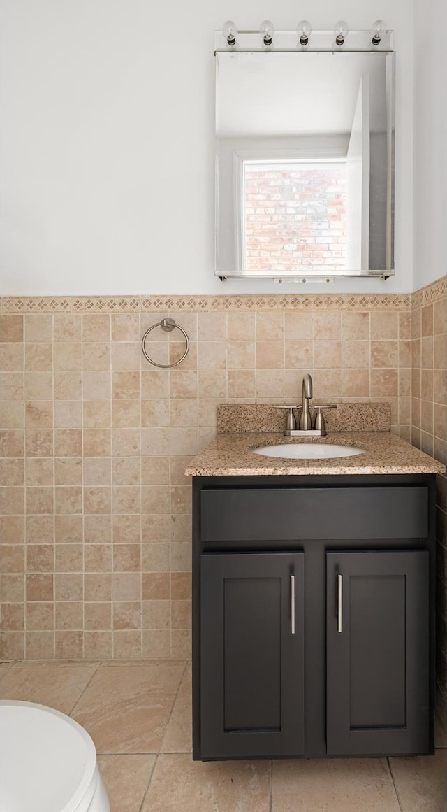 bathroom with tile walls, vanity, tile patterned floors, toilet, and wainscoting