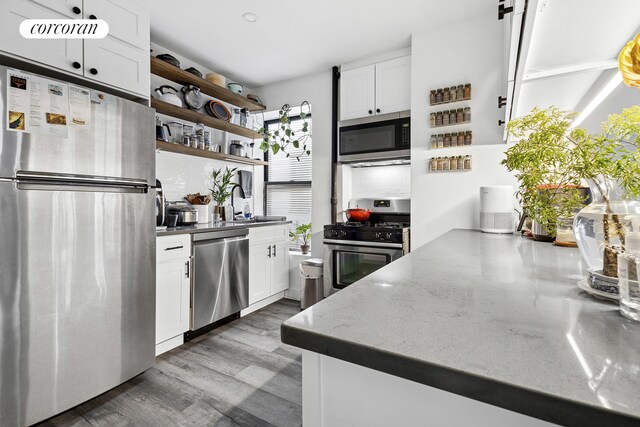 551 W 160th St Unit 5B, New York City, NY 10032 - kitchen with stainless steel appliances, open shelves, white cabinets, and wood finished floors
