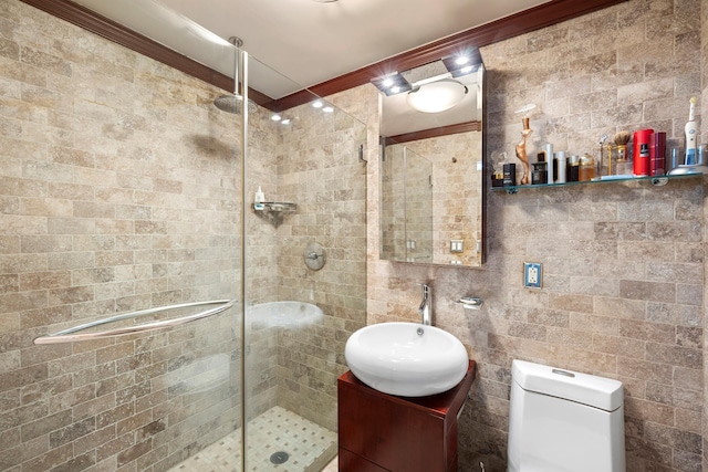 bathroom with tile walls, a shower stall, toilet, vanity, and crown molding
