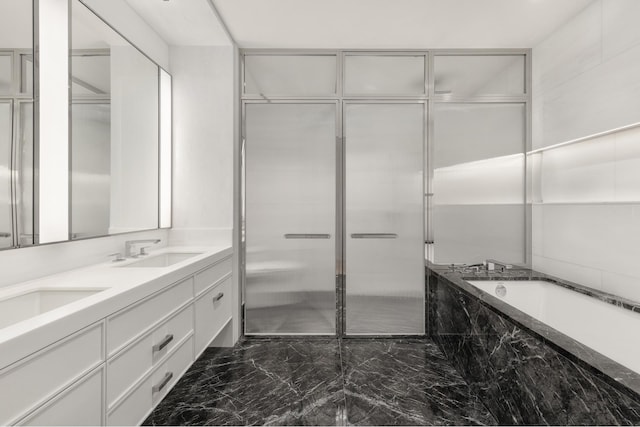 full bath with a bath, marble finish floor, a sink, and double vanity
