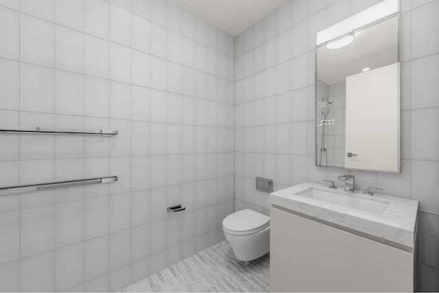 full bathroom featuring a tile shower, toilet, vanity, and tile walls