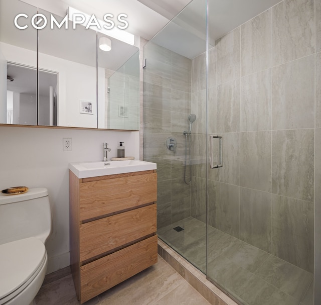 bathroom with a stall shower, toilet, and vanity
