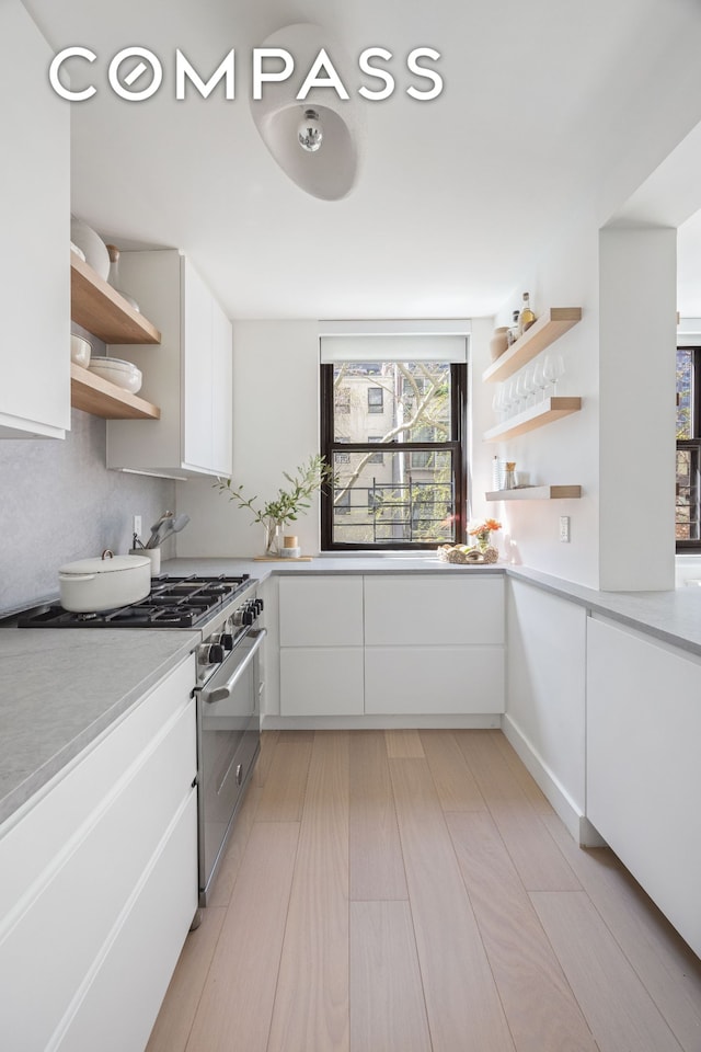 kitchen with open shelves, stainless steel range, light countertops, white cabinets, and modern cabinets