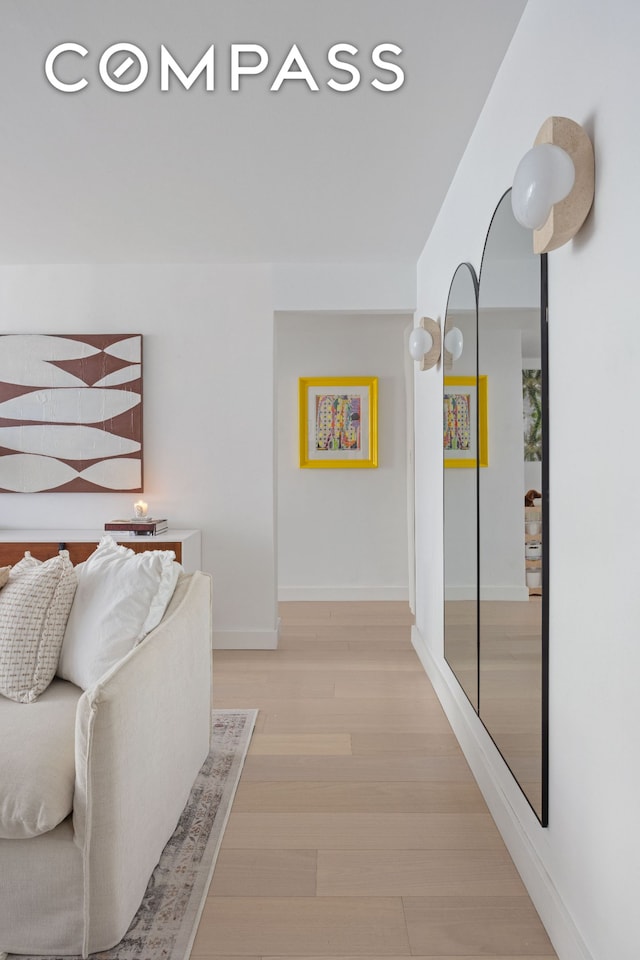 corridor with light wood-type flooring and baseboards