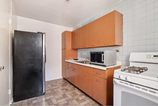 1010 Sherman Ave Unit 5L, New York City, NY 10456 - kitchen with white range with gas cooktop, freestanding refrigerator, light countertops, backsplash, and a sink