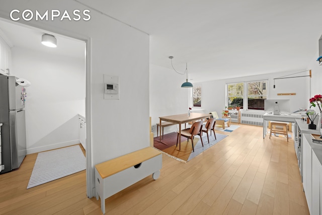 interior space with radiator heating unit, baseboards, and light wood-type flooring