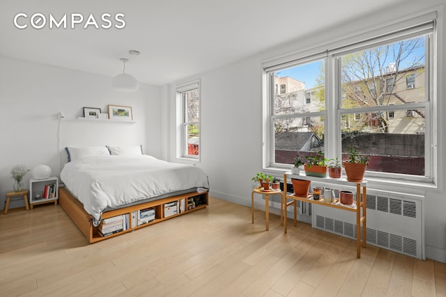 bedroom featuring radiator, baseboards, and wood finished floors