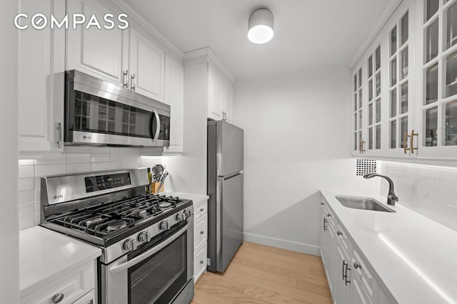kitchen with white cabinets, decorative backsplash, stainless steel appliances, and a sink