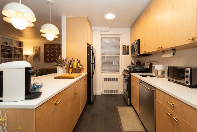 kitchen featuring radiator, dark tile patterned flooring, appliances with stainless steel finishes, light countertops, and a toaster