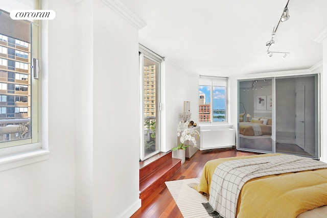 bedroom with ornamental molding and wood finished floors