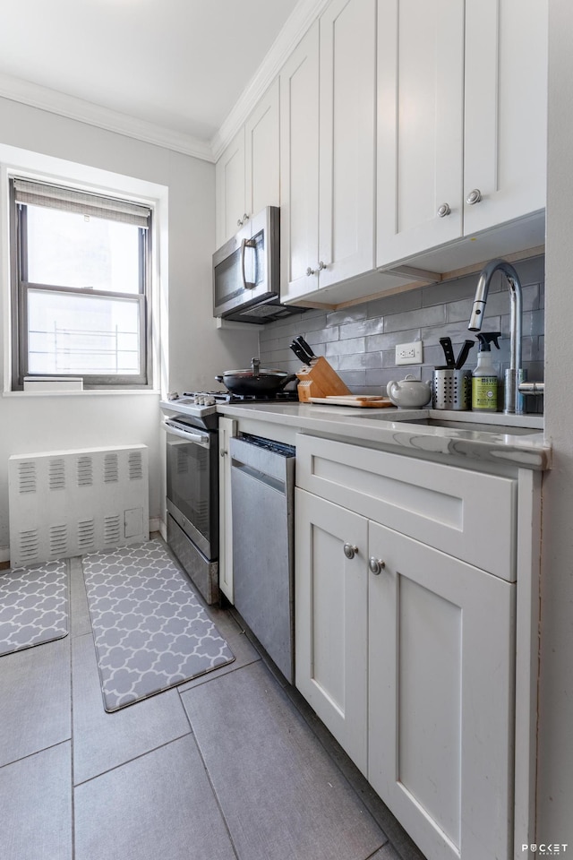 kitchen with stainless steel appliances, white cabinetry, crown molding, decorative backsplash, and light countertops