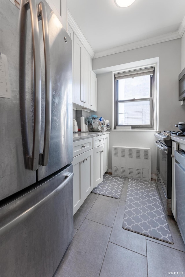 kitchen featuring appliances with stainless steel finishes, ornamental molding, white cabinetry, and tile patterned floors