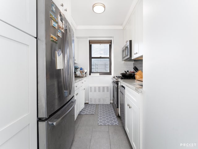 kitchen with appliances with stainless steel finishes, light countertops, white cabinets, and ornamental molding