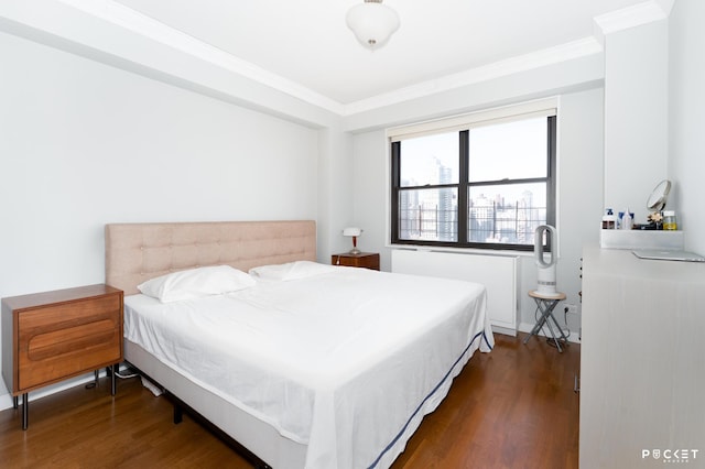 bedroom with ornamental molding and wood finished floors