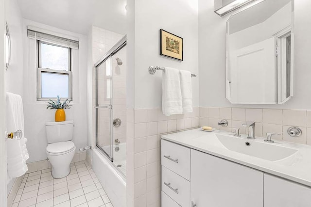 bathroom with toilet, tile patterned floors, vanity, and bath / shower combo with glass door