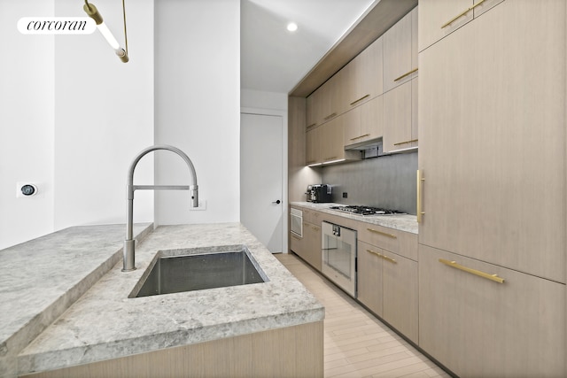 91 Leonard St Unit 2E, New York City, NY 10013 - kitchen with a sink, light brown cabinets, stainless steel gas stovetop, light wood-type flooring, and modern cabinets