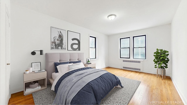 bedroom with baseboards, light wood finished floors, and radiator