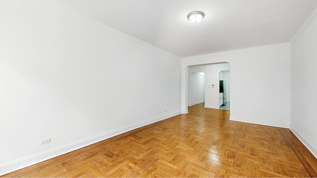 spare room with baseboards, arched walkways, and crown molding
