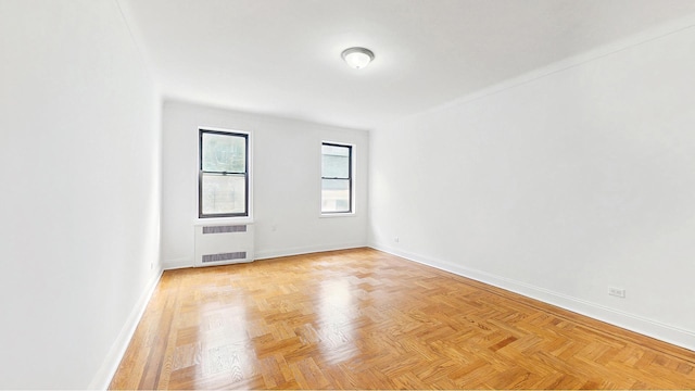 spare room featuring baseboards and radiator