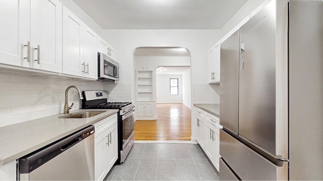 kitchen featuring light countertops, stainless steel appliances, white cabinetry, and a sink