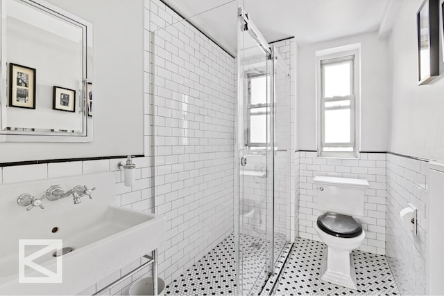 414 E 52nd St Unit 2A, New York City, NY 10022 - bathroom with tile walls, a stall shower, tile patterned floors, and a wainscoted wall