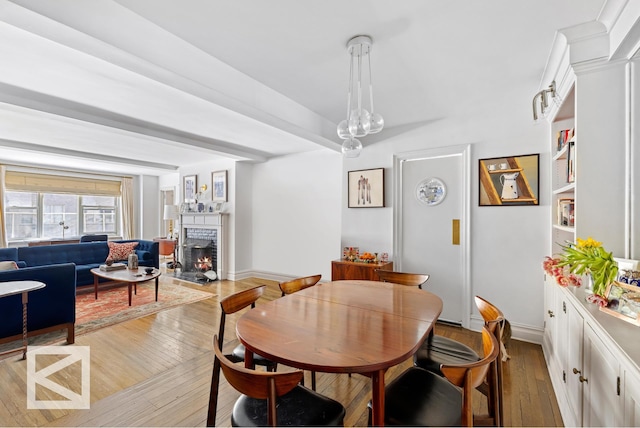 414 E 52nd St Unit 2A, New York City, NY 10022 - dining room featuring wood-type flooring and a lit fireplace