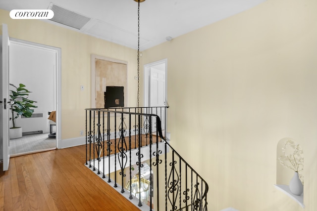 hallway with baseboards, an upstairs landing, wood finished floors, and visible vents