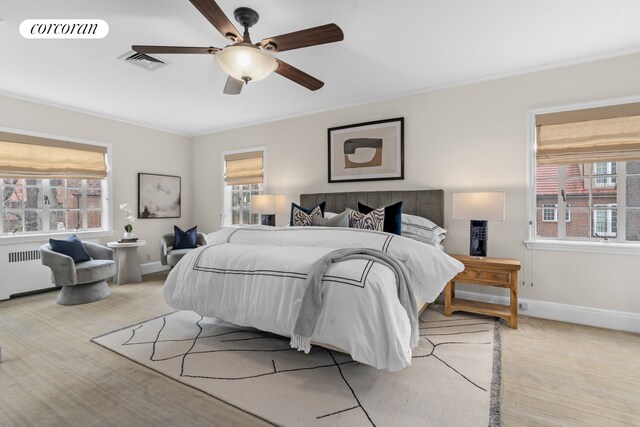 bedroom with visible vents, radiator heating unit, and multiple windows