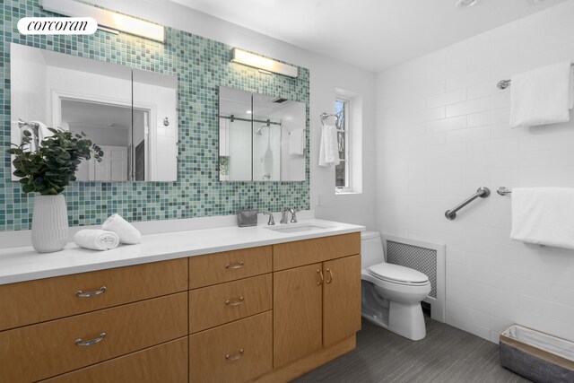 bathroom featuring vanity, toilet, tile walls, visible vents, and a stall shower
