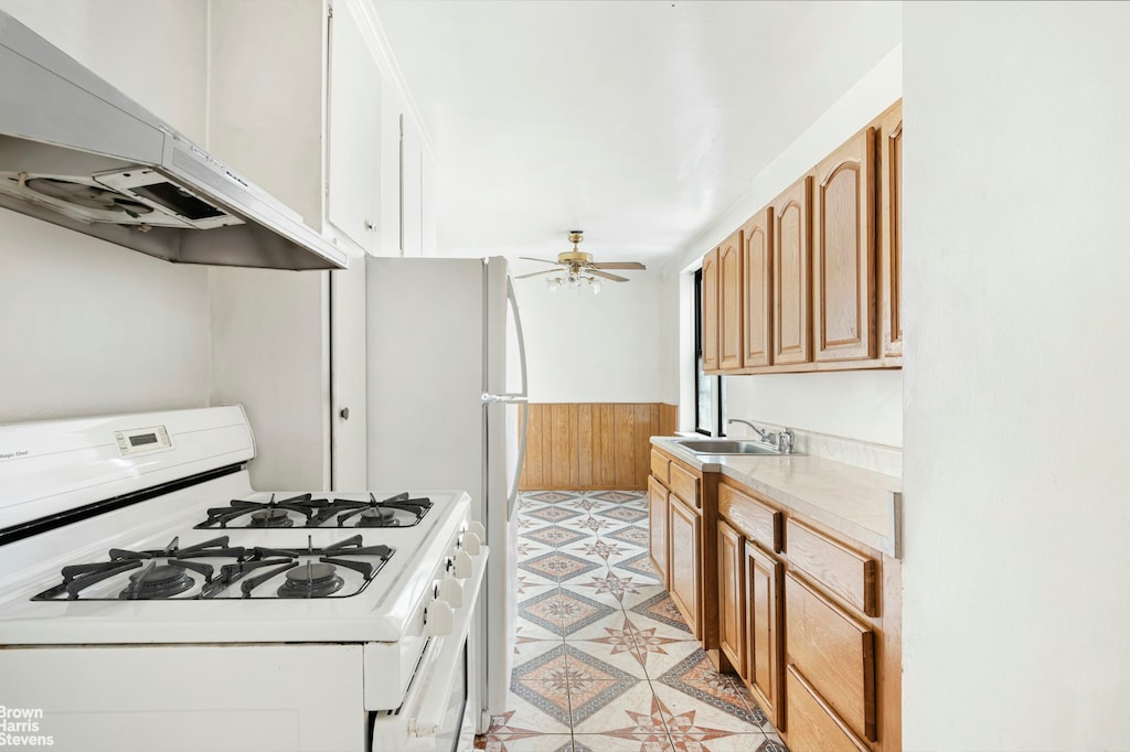 740 E 232nd St Unit 6H, New York City, NY 10466 - kitchen featuring gas range gas stove, under cabinet range hood, ceiling fan, a wainscoted wall, and a sink