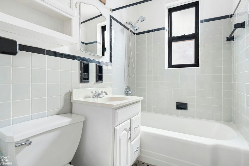 full bathroom featuring toilet,  shower combination, tile walls, and vanity